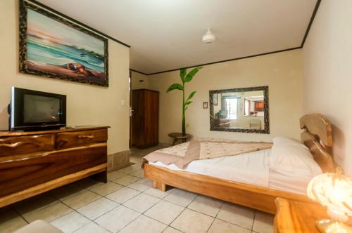 a bedroom with a bed and a flat screen tv at Cadillac Rock Beach Hotel in Jacó