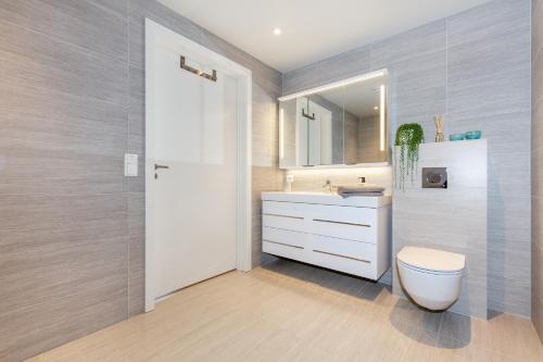 a bathroom with a white toilet and a sink at Modern Apartment with panorama wiew in Blakset