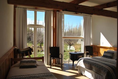 a bedroom with two beds and a large window at Hostería de la Patagonia in Chile Chico