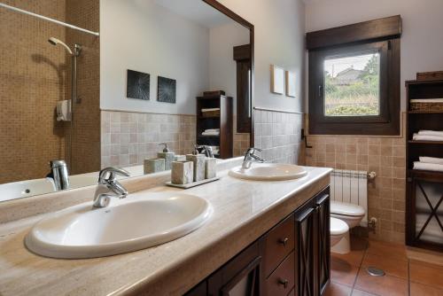 a bathroom with two sinks and a toilet at Casa A Pedriña in Amés