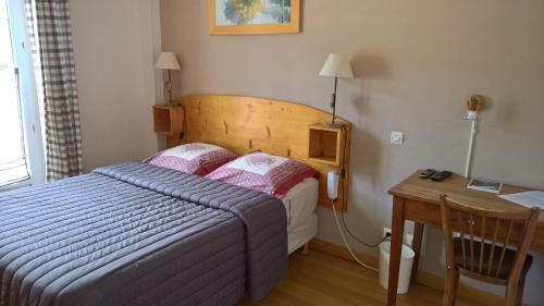 um quarto com uma cama e uma secretária com um telefone em Les Fauvettes em Saint-Léger-les-Mélèzes