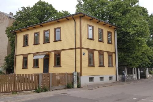 a yellow house with a wooden fence at Сhocolate Factory Apartment Nr.2 in Riga