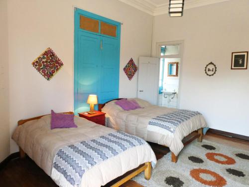 2 camas en una habitación con puerta azul en Park Hostel, en Arequipa