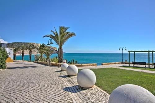 a cobblestone walkway with white balls in front of the ocean at Luz Beach Luxury Apartment in Luz