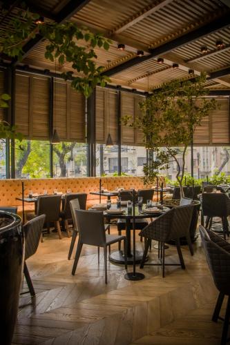 a restaurant with tables and chairs and windows at Brick Hotel Mexico City - Small Luxury Hotels of the World in Mexico City