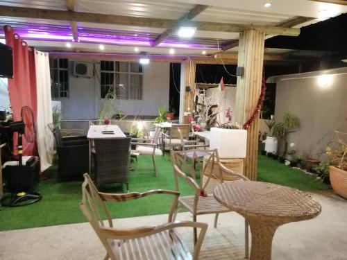 Residence Les Bambous B&B في ماهيبورغ: غرفة بها كراسي وطاولات وأرضية خضراء