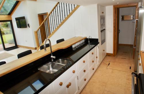 a kitchen with a sink and a staircase at Southrepps BarnHam in Cromer