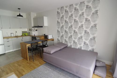 uma sala de estar com um sofá roxo e uma cozinha em Apartament 5e em Szczecin