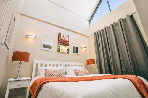 a bedroom with a white bed with green curtains at Eden on the bay 217A-Penthouse in Cape Town