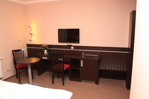 a hotel room with a desk with a tv on the wall at Penzion Na Netřebě in Pardubice