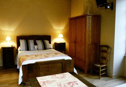 Schlafzimmer mit einem Bett und einem Holzschrank in der Unterkunft Les gîtes du bourg in Vitrac