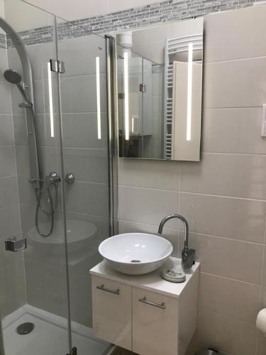 La salle de bains est pourvue d'un lavabo et d'une douche avec un miroir. dans l'établissement Bervia Apartman, à Szombathely
