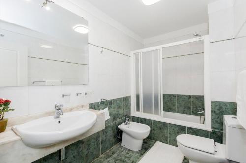 a white bathroom with a sink and a toilet at Family apartment in Adeje