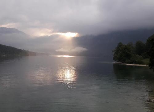 a view of a lake with the sun shining on the water at Snežak (Snowman) in Bohinj