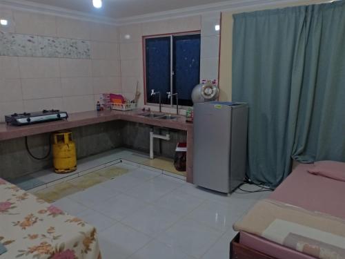 a kitchen with a sink and a refrigerator in a room at Homestay pekan ranau in Ranau