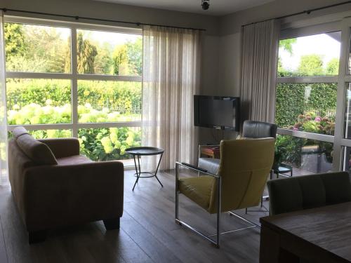 a living room with a couch and chairs and a television at Appartement B&B De Koning in Afferden
