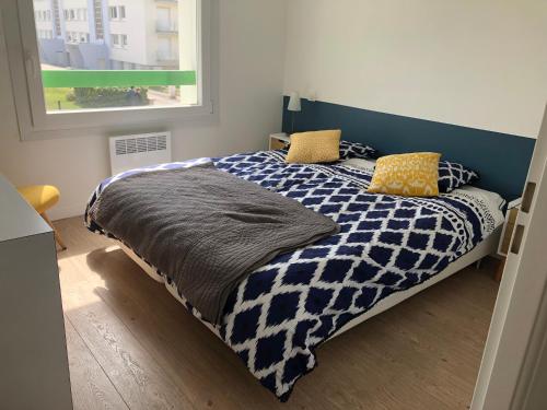 Schlafzimmer mit einem Bett mit einer blauen und weißen Bettdecke in der Unterkunft Le grand Bleu in Wimereux