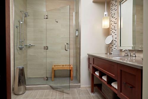 uma casa de banho com uma cabina de duche em vidro e um banco. em Rizzo Center, a Destination by Hyatt Hotel em Chapel Hill