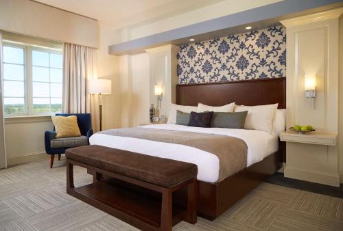 a hotel room with a large bed and a chair at Rizzo Center, a Destination by Hyatt Hotel in Chapel Hill