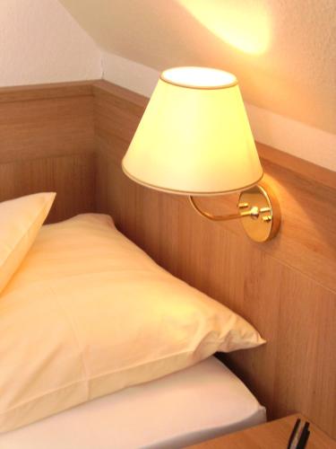 a lamp on a wall next to a bed at Landhotel Halbfas-Alterauge in Drolshagen