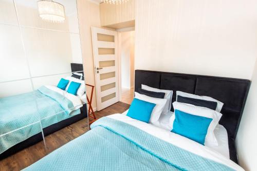 sypialnia z 2 łóżkami i białymi i niebieskimi poduszkami w obiekcie Super-Apartamenty Targi Poznańskie w Poznaniu