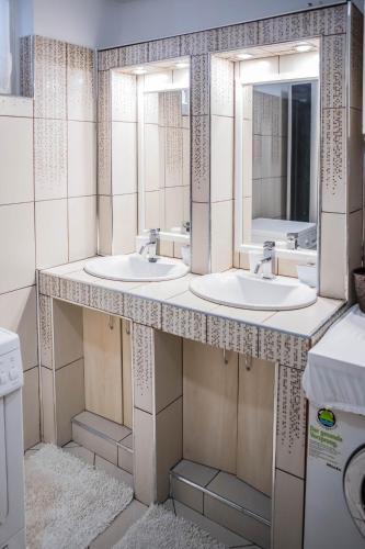 a bathroom with two sinks and two mirrors at Virág Vendégház in Makó