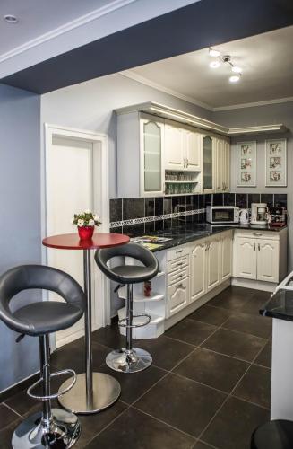 a kitchen with white cabinets and a red table at Virág Vendégház in Makó