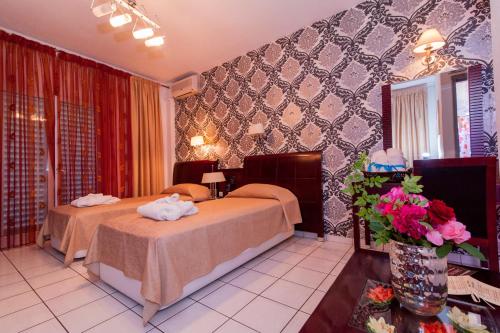 a hotel room with two beds and a vase of flowers at Krikonis Hotel in Ioannina