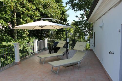 Montescudo的住宿－Casa Ugolini since 1857，庭院配有椅子、遮阳伞和桌子。