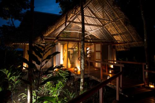 a small house with a thatched roof at night at Inkaterra Reserva Amazonica in Puerto Maldonado