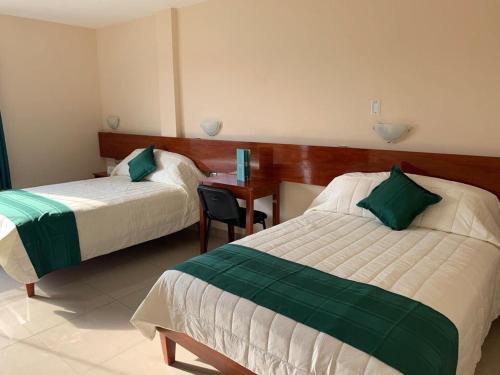 una camera d'albergo con due letti e una scrivania di Tariri Hotel a Pucallpa