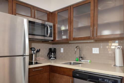 a kitchen with wooden cabinets and a stainless steel refrigerator at Staybridge Suites - Gilbert - East Mesa by IHG in Gilbert