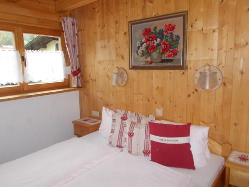 Schlafzimmer mit einem Bett mit weißer Bettwäsche und roten Kissen in der Unterkunft Haus Waldruh in Niederau