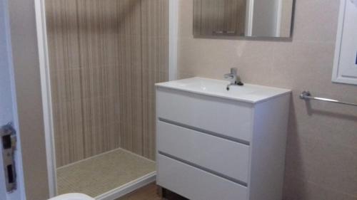 La salle de bains blanche est pourvue d'un lavabo et d'une douche. dans l'établissement CASA DO SANTO, à Lobios