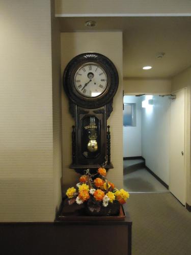 a clock on the wall in a hallway with flowers at Yamagisi Ryokan in Fujikawaguchiko