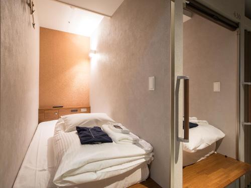a room with two beds with white sheets at Gardens Cabin in Sapporo