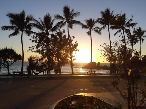 a sunset at the beach with palm trees at Whitsunday Sands Resort in Bowen