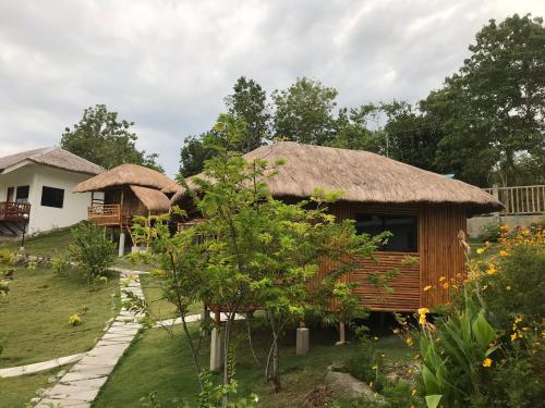 a house with a thatched roof and a garden at Cuestas Beach Resort and Restaurant in Badian