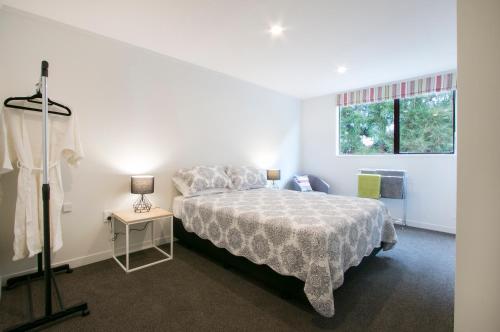 a white bedroom with a bed and a window at Hydrangea Cottage in Katikati