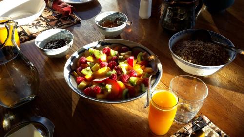 a bowl of fruit on a wooden table with orange juice at Paramata Lodge in Kakapotahi