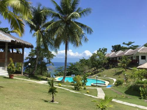 a view of a resort with a swimming pool and palm trees at Cuestas Beach Resort and Restaurant in Badian