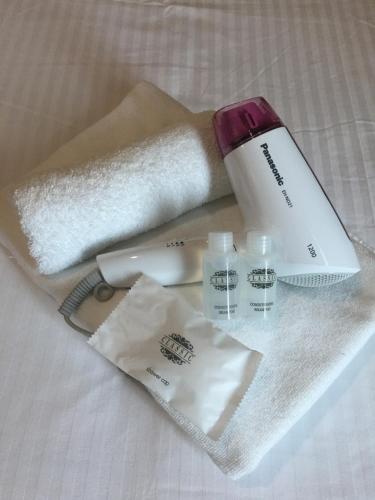 a set of towels and a bottle of cosmetics on a bed at Chemara Boutique Hotel in Miri