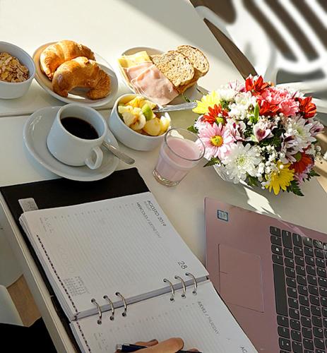 a table with a laptop computer and a plate of food at Amerian Rafaela Hotel in Rafaela