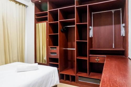 a room with a large wooden cabinet next to a bed at Spacious High Floor 2BR at Taman Beverly Apartment By Travelio in Surabaya