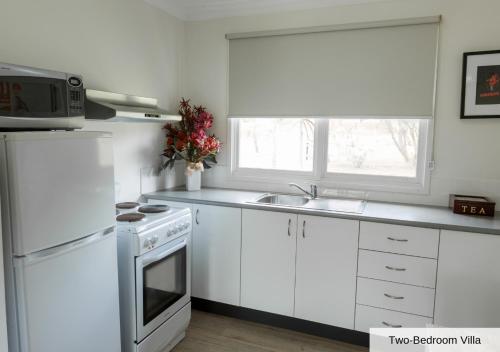 a kitchen with white cabinets and a white stove top oven at Pokolbin Village Estate in Pokolbin