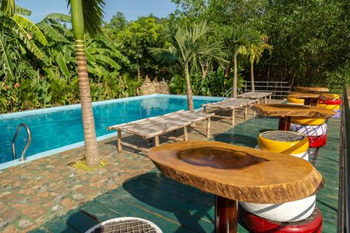 a table and benches next to a swimming pool at Jungle Boss Homestay in Phong Nha
