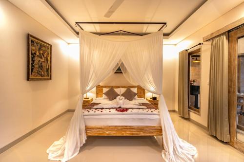a bedroom with a canopy bed with white drapes at Puri Sedana Ubud Villa in Ubud