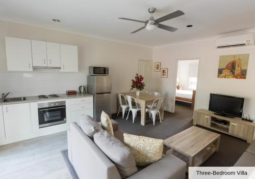 a living room with a couch and a kitchen with a table at Pokolbin Village Estate in Pokolbin