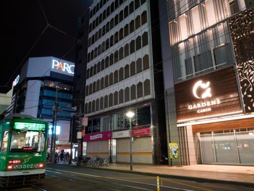 a green bus driving down a city street at night at Gardens Cabin in Sapporo