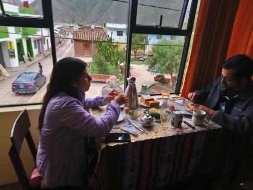 San Pedro的住宿－Hostal Inca，坐在餐桌旁吃食物的男人和女人